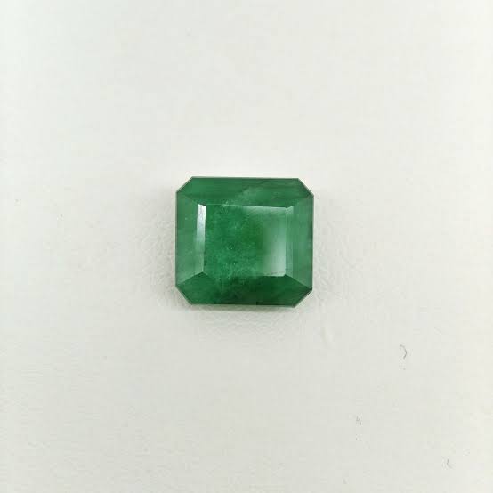 Loose rectangular green emerald with clipped corners on a white background